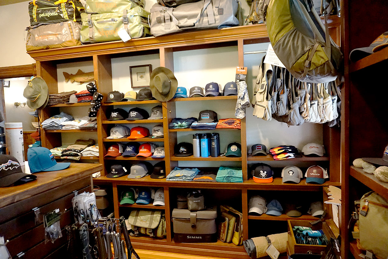 Retail section of St. Peter's Fly Shop, showing stacks of clothing, hats and bags.