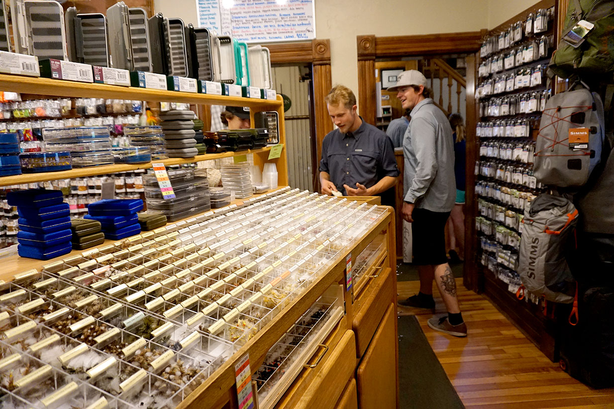 Two people examine the selection of flys in a fly shop