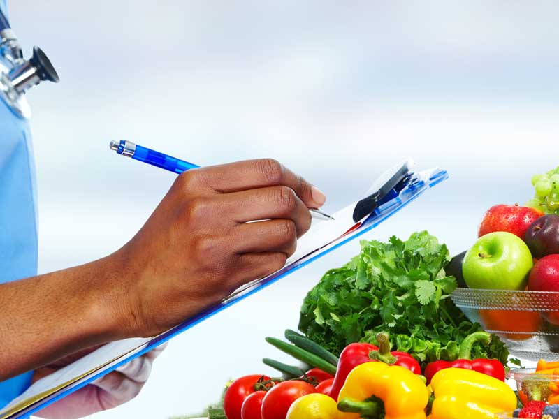 A medical professional fills out form on clipboard overlooking vegetables